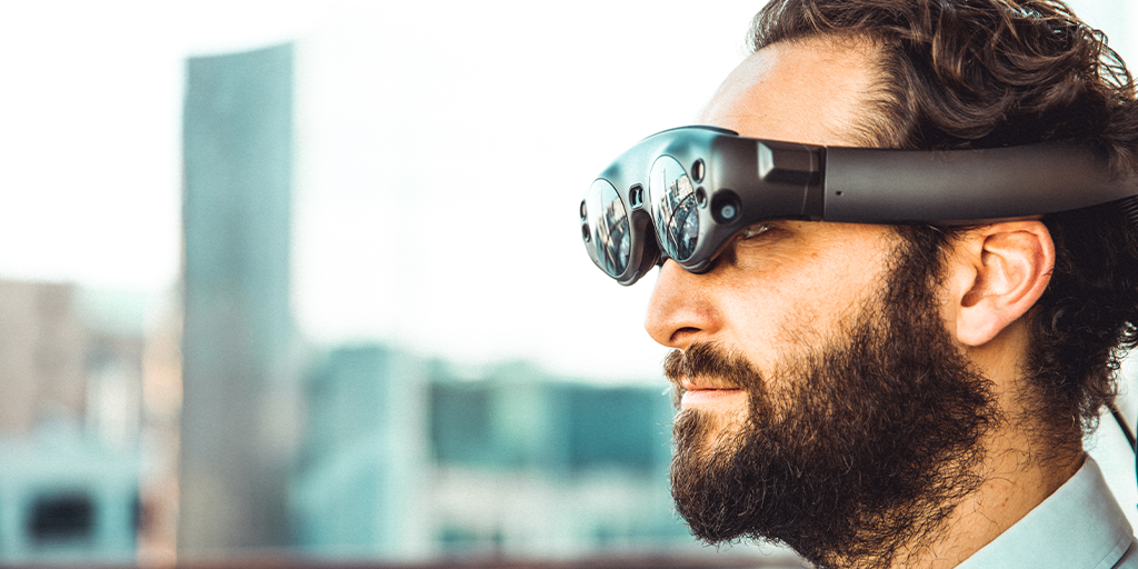 Seeking: AR/VR Training System Best Practices.. Image of a bearded man wearing a magic leap headset in front of a blurred city scape
