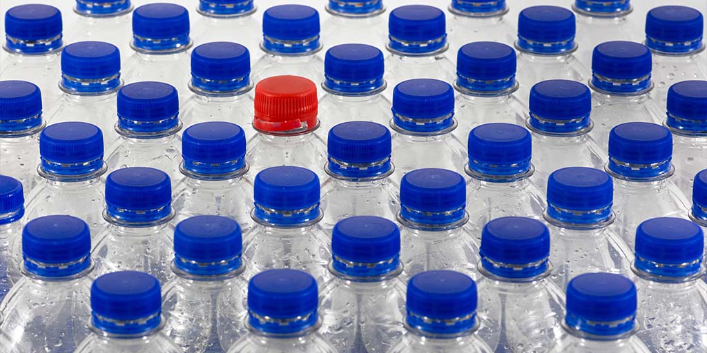 PepsiCo Seeking: Tech for Improving Mechanical rPET Quality-Image of the tops of bottles with all blue caps except a single red cap.