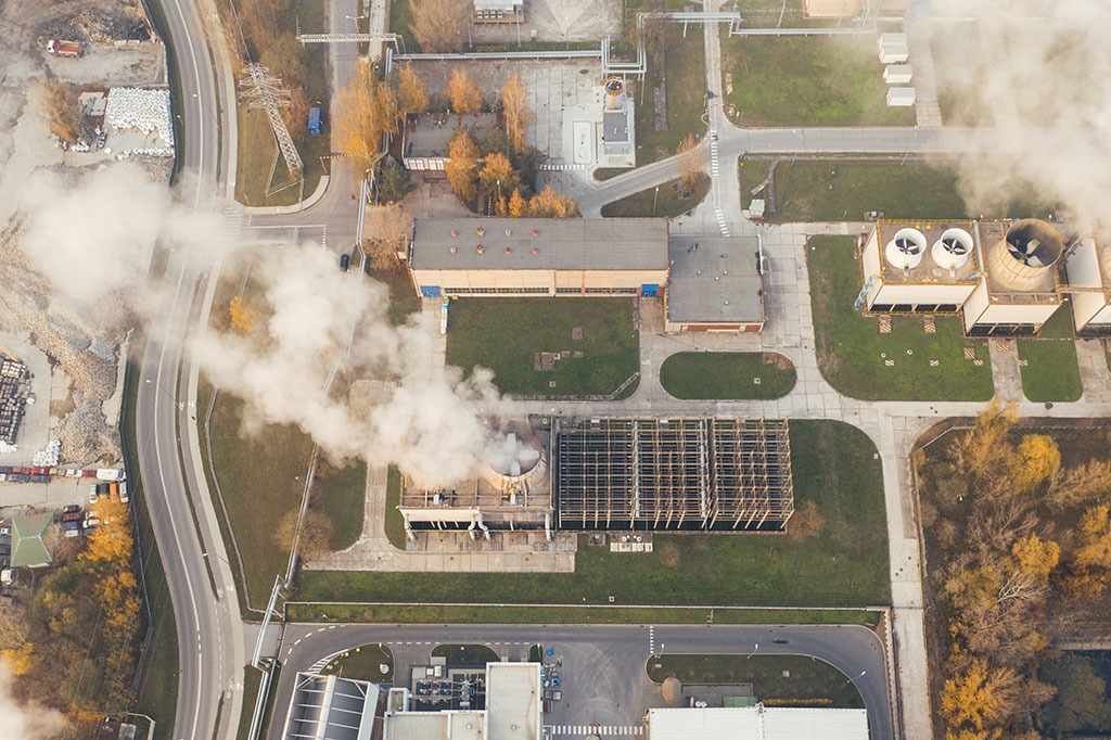 Carbon Capture Technologies for Industrial Applications-Aerial view of smokestacks in an industrial park emitting a column of smoke or water vapor