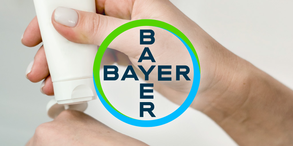 Bayer logo over hands holding flexible tube packaging dispensing lotion